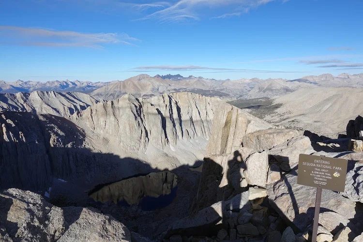 The sign at Trail Crest marks the entrance to Sequoia National Park above a basin of lakes and sheer cliffs.