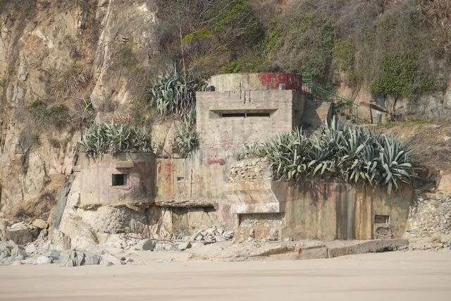 A concrete defensive structure is built into the rocky edge of the beach.