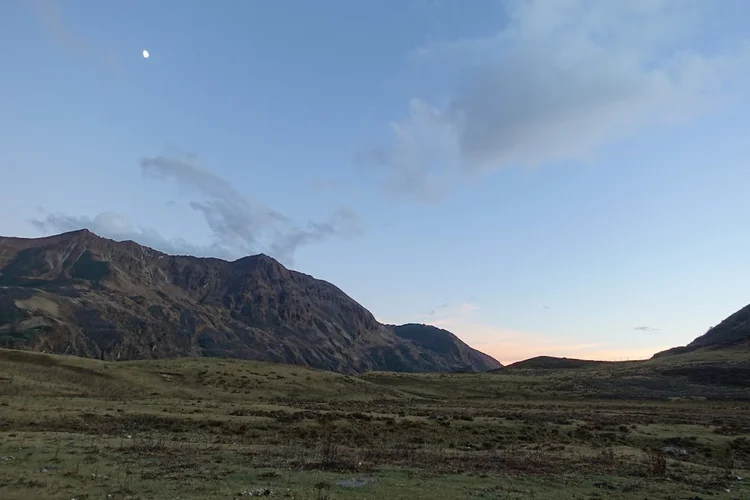 The moon hangs over Tongphushong as the light fades beyond the ridge.