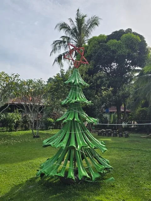 A Christmas-tree decoration made from palm leaves stands beside the route into the forest.