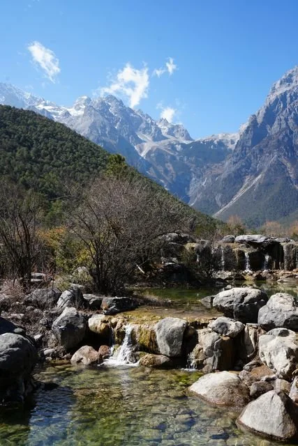 Water spills between rocks below Yulong Snow Mountain in Blue Moon Valley.