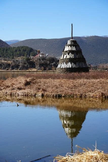 A pointed stone monument is reflected in a quiet pool.