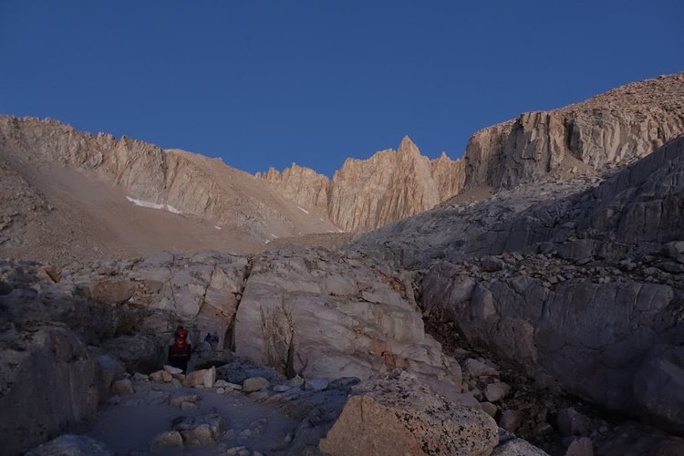 Small hikers follow the rocky path beneath the towering granite spires of the upper basin.