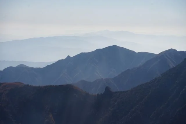 Mountain ridges recede through layers of blue-grey haze.