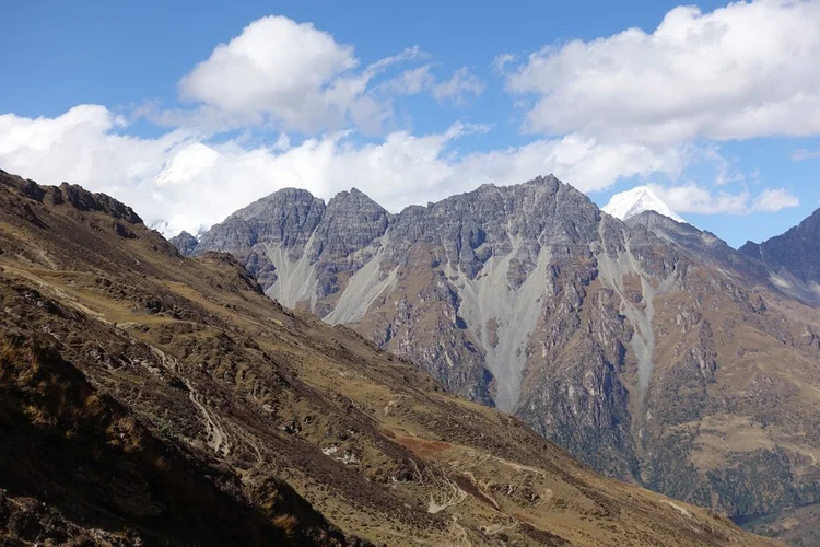 White summits emerge from the clouds beyond the dark ridge on the climb towards Takulungla.