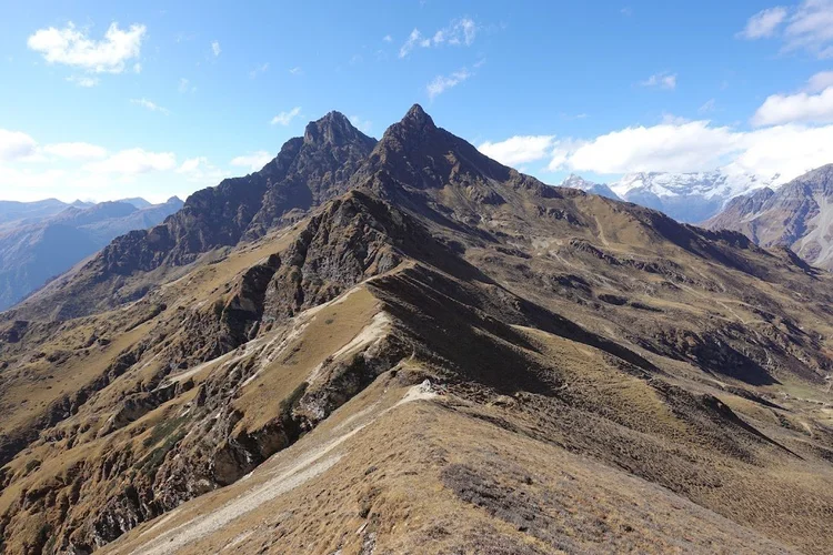 A narrow path follows the ridge away from Takulungla, with cairns and flags marking the way.