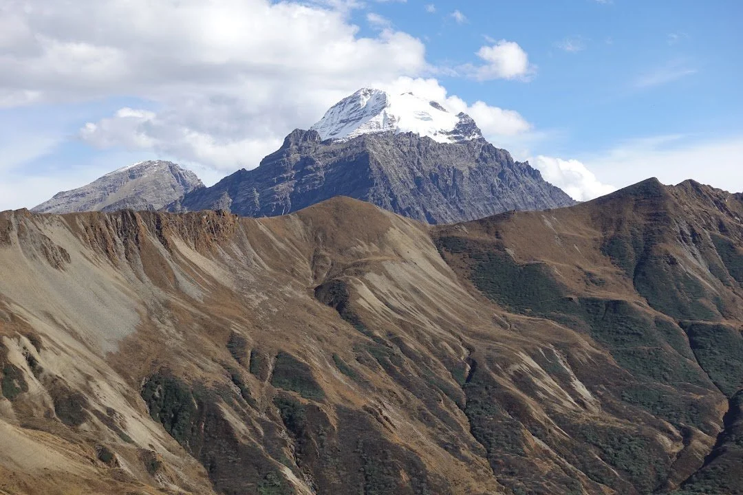 A snow-capped summit rises beyond the bare, eroded slopes near Takulungla Pass.