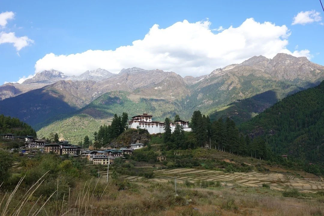 A white-walled hilltop complex overlooks village houses and terraced fields after the trek.