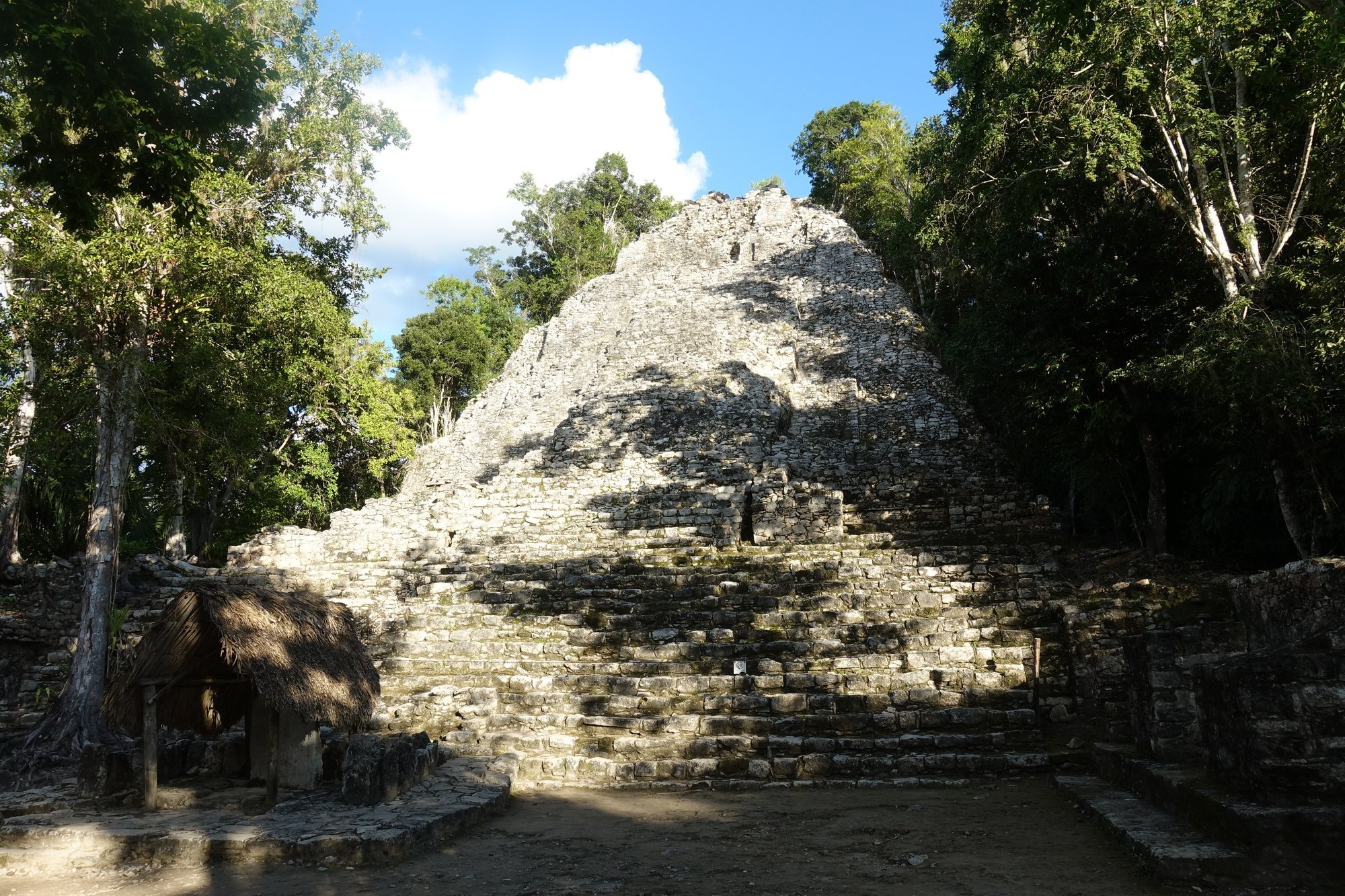 A stone pyramid rises through the trees at Cobá.