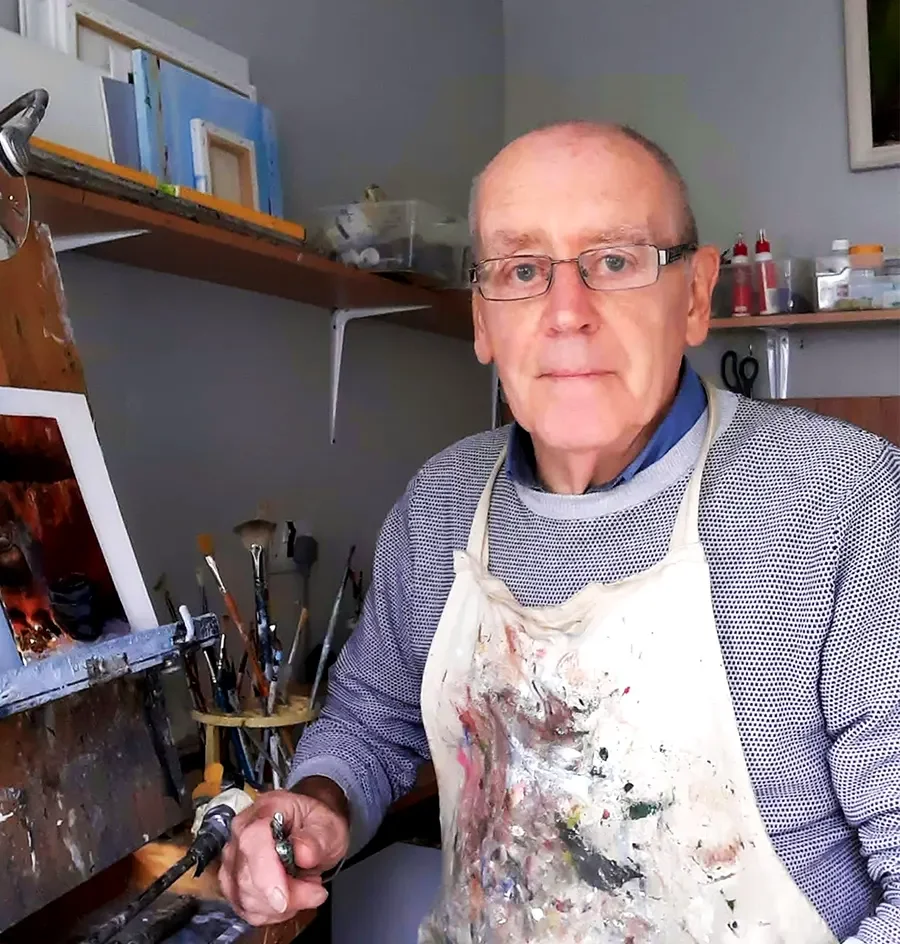 David Minehan at work in his studio, brushes in hand, in front of a painted dresser