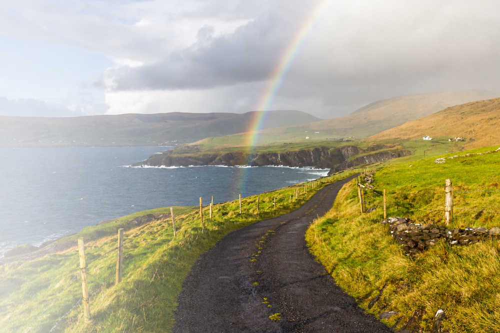A rainbow over the Atlantic, falling across a road above the cliffs
