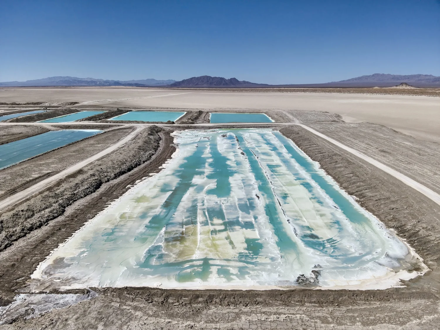 Top-down drone view of salt extraction ponds and a stockpile