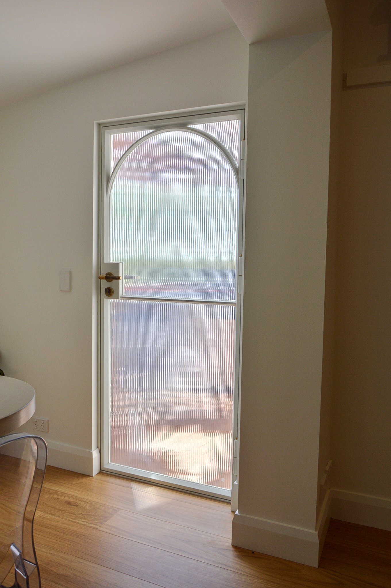 Custom matt white steel door with arched detailing, fluted glass and brass hardware
