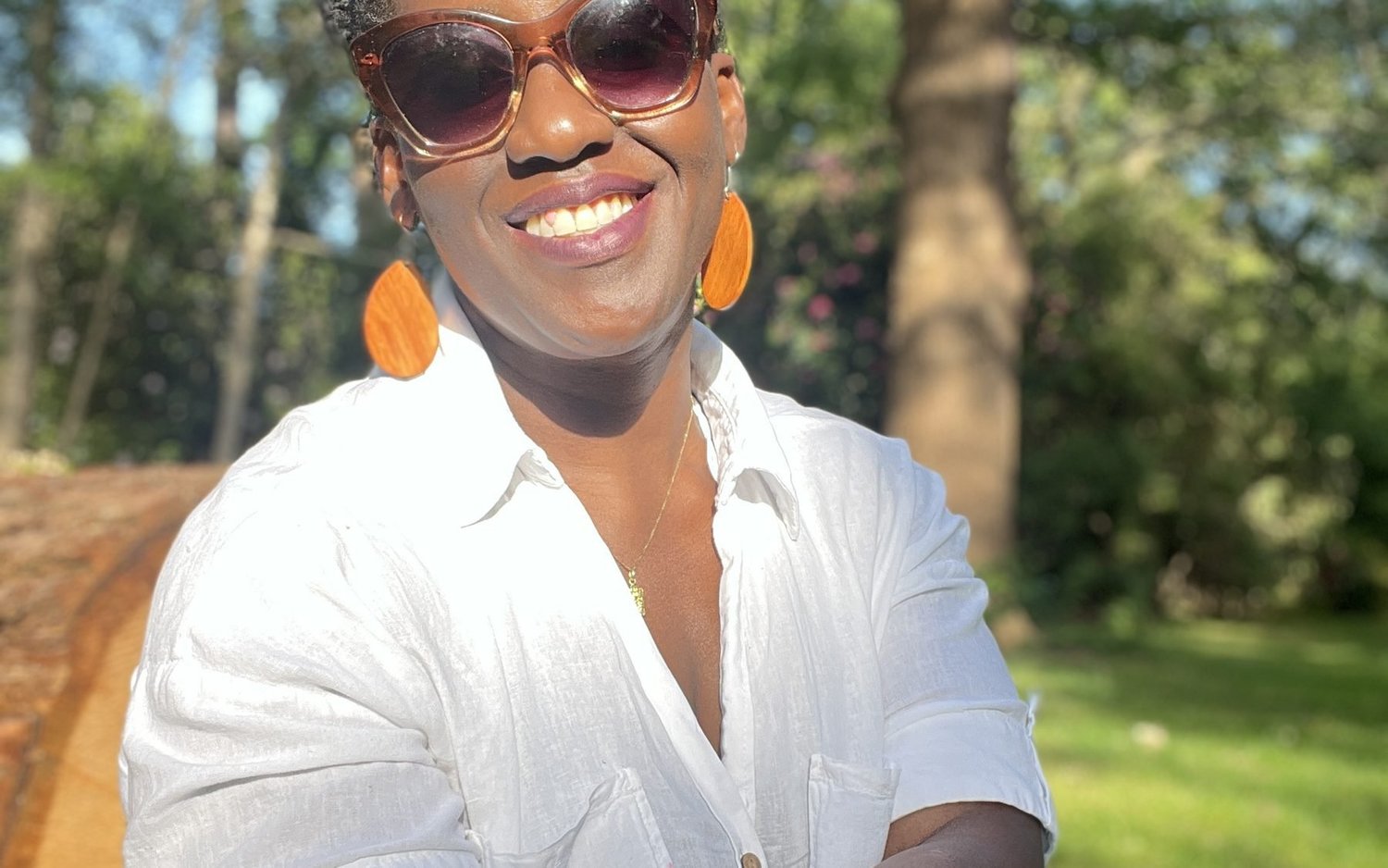 Timi Phillips outdoors in a London park, smiling towards the camera