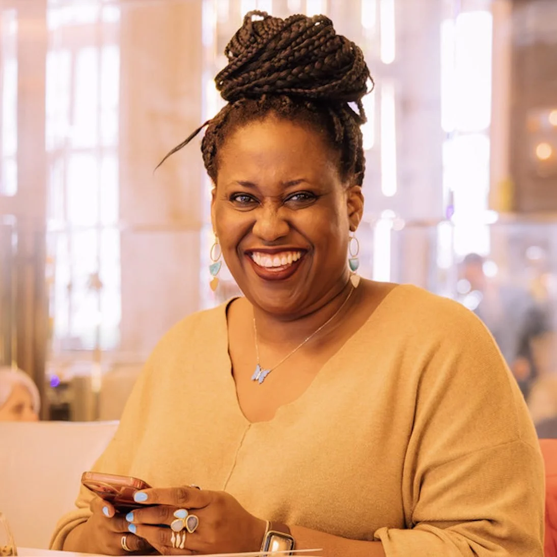 Timi Phillips laughing, seated in a warmly lit room