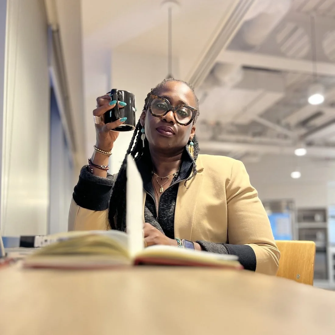 Timi Phillips working with an open book and a coffee