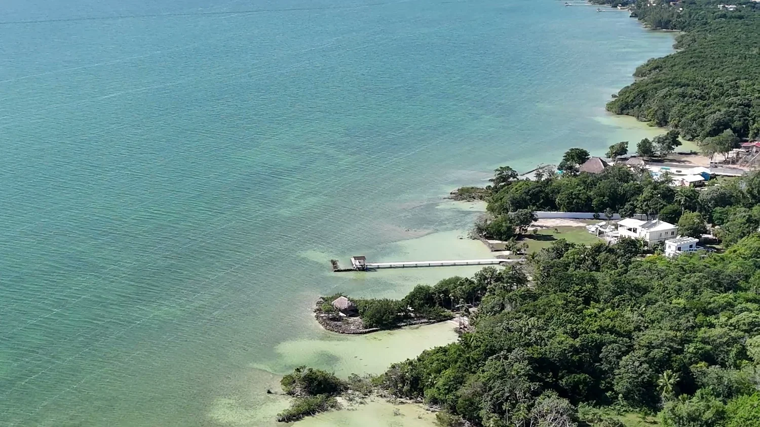 Shallow turquoise water of Corozal Bay under a clear sky, seen from above