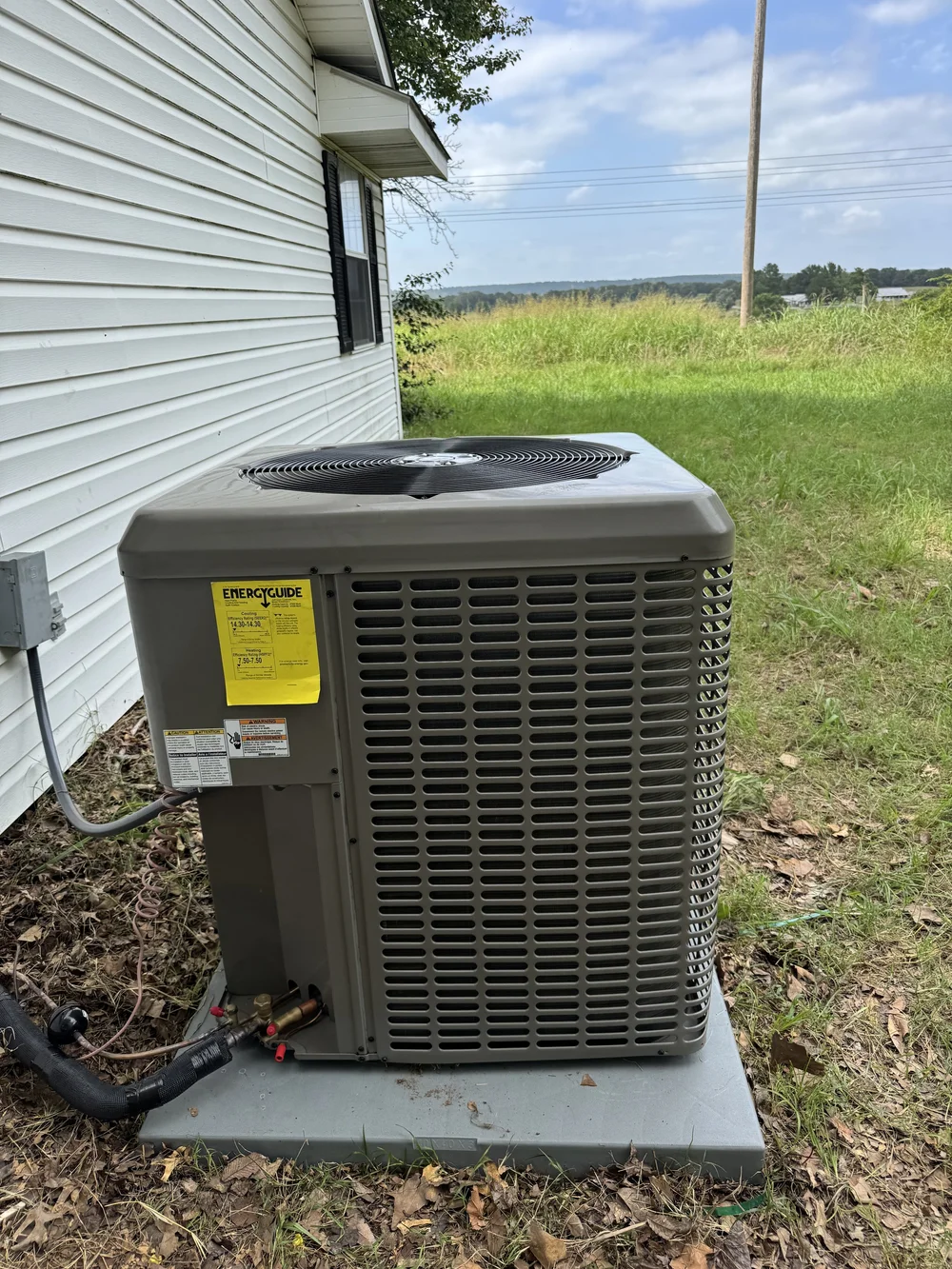 The old AC condenser beside a lap-siding home near Keota, OK, before Clark HVAC removed and replaced it