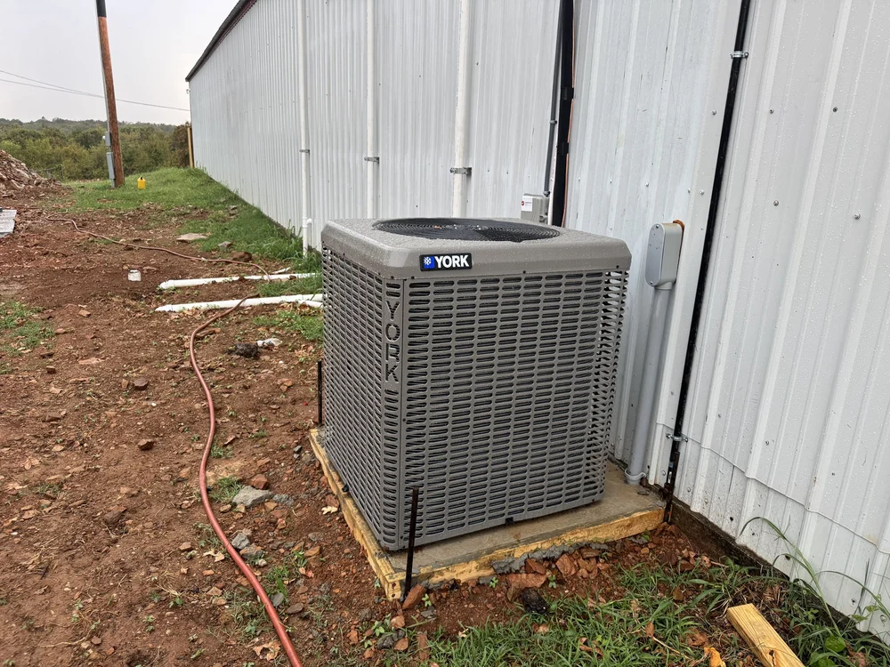 York AC condenser installed by Clark HVAC beside a metal building shop in rural Sequoyah County near Sallisaw, OK