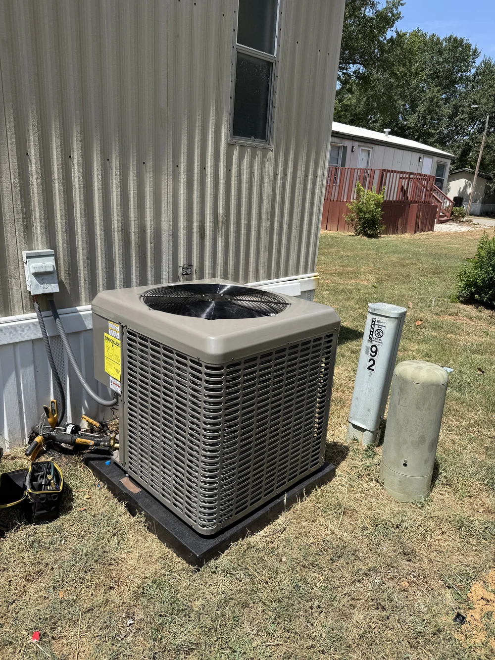 Clark HVAC charging a new York AC condenser with gauges at a mobile home in Van Buren, AR