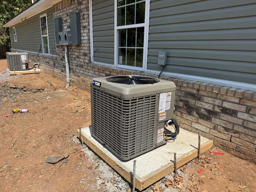 New York AC condenser on a concrete pad at a new-construction brick and siding home in Van Buren, AR, installed by Clark HVAC