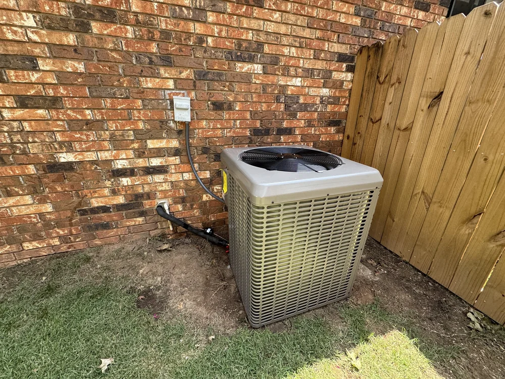 The worn-out AC condenser at a brick home in south Fort Smith, AR, before Clark HVAC replaced it