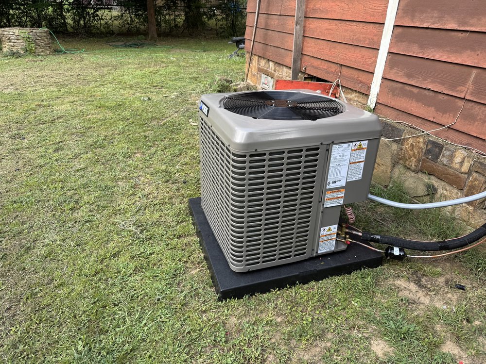 New York air conditioner condenser on a pad beside a home in Spiro, OK, installed by Clark HVAC