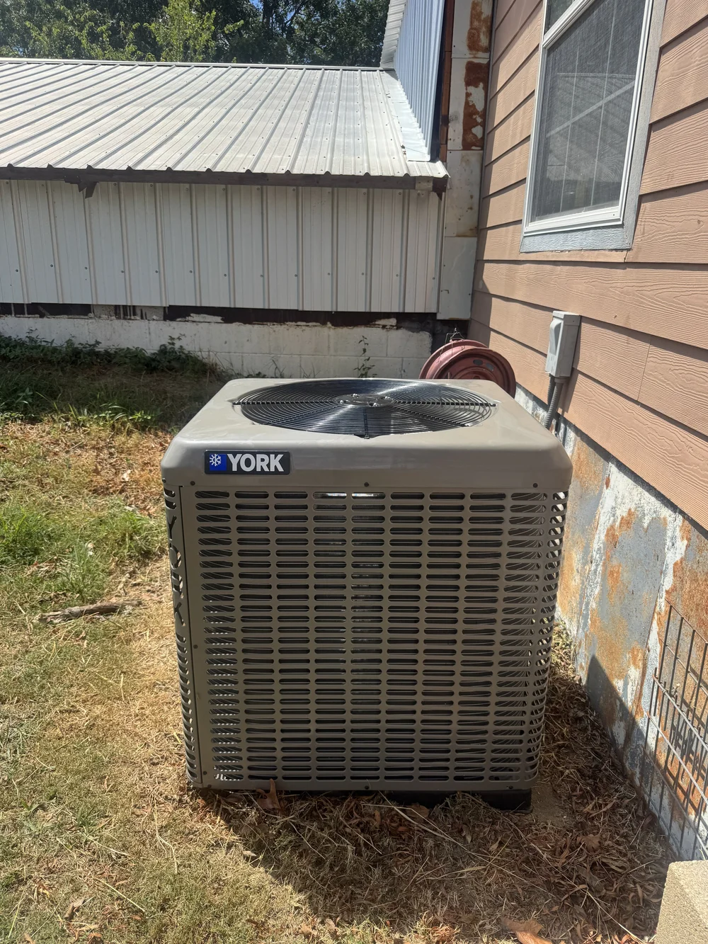 New York AC condenser beside a rural lap-siding home near Keota, OK, installed by Clark HVAC