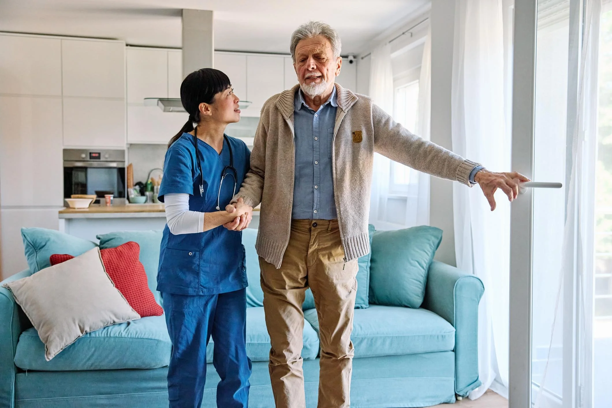 Care professional supporting an older man as he stands and walks at home