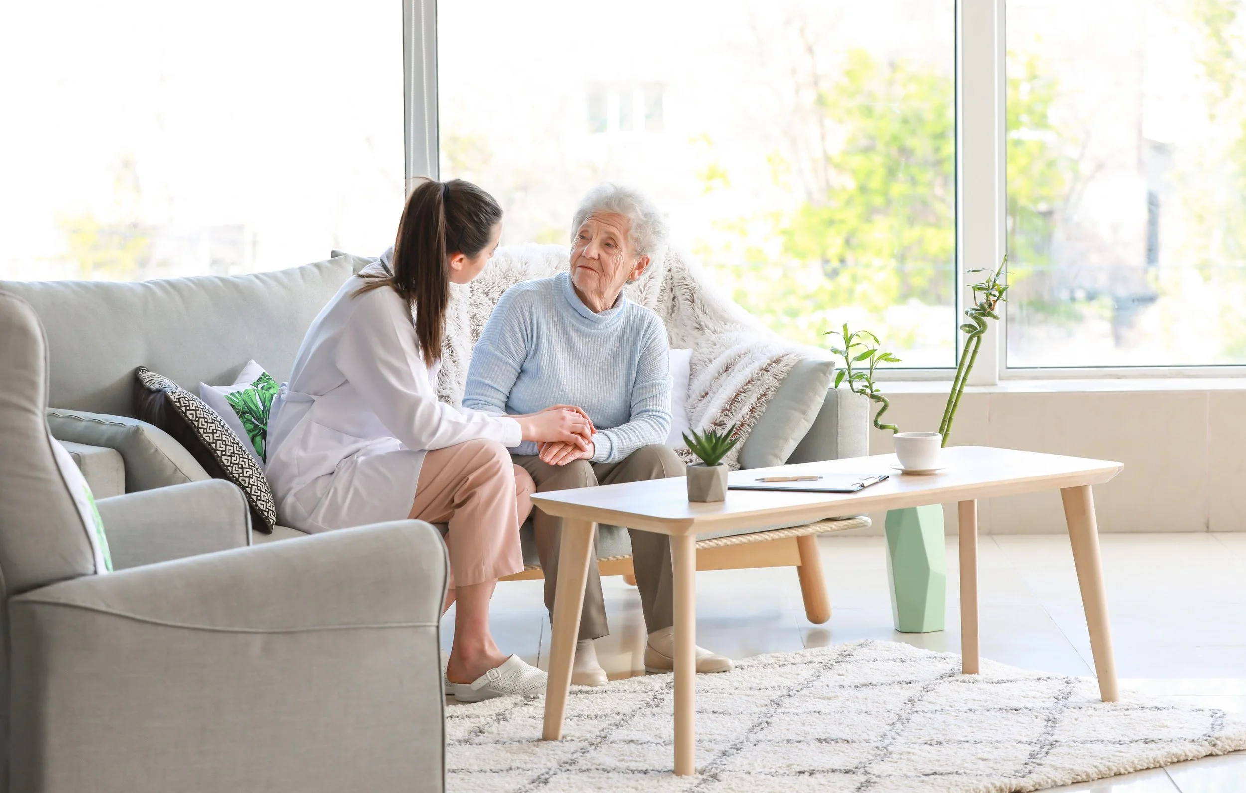 Care professional listening closely to an older woman at home