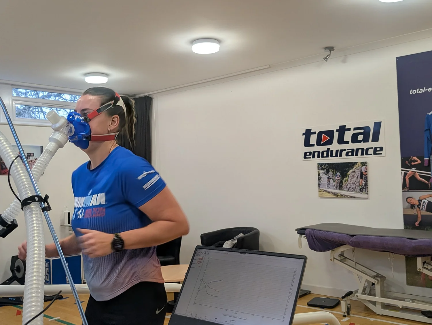 Triathlete mid-test on the treadmill in the Total Endurance lab, with live results on screen