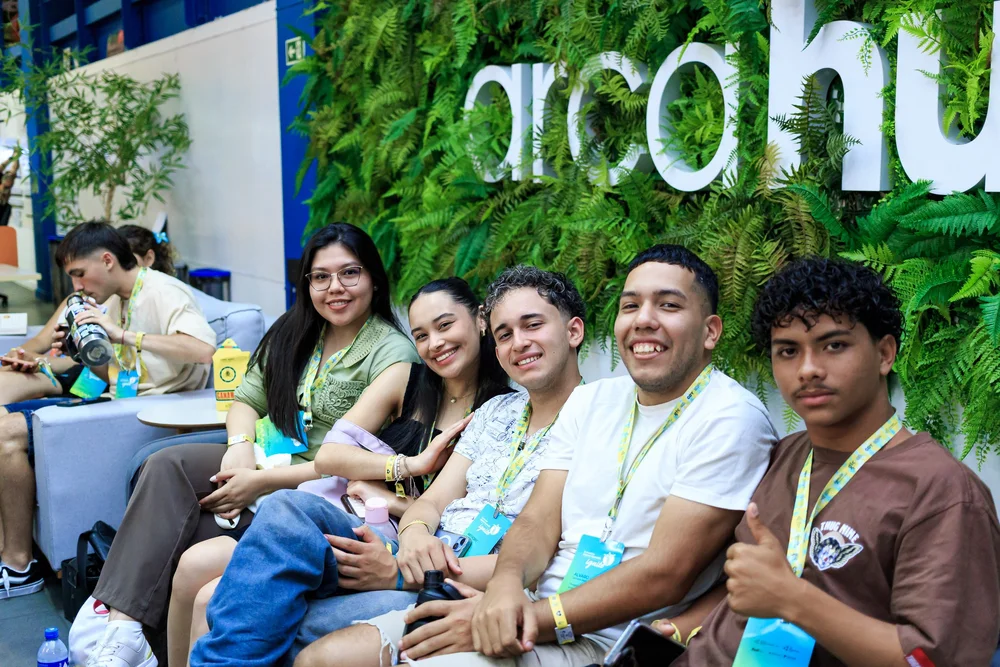 Alumni smiling together in front of a green wall at a regional event