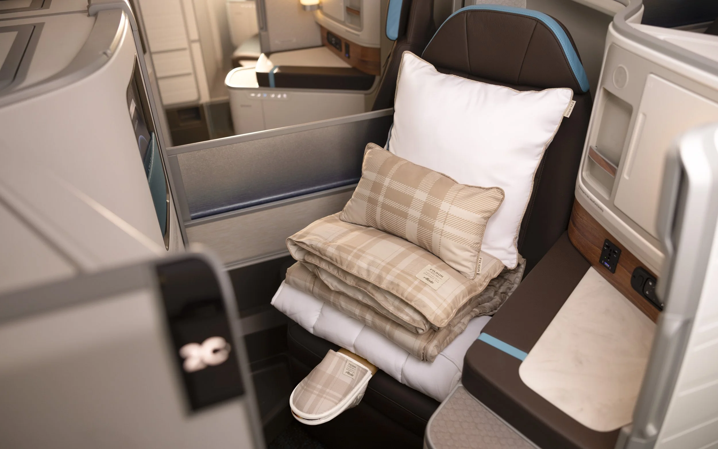 Alaska Airlines international business class suite with a lie-flat seat and personal entertainment screen