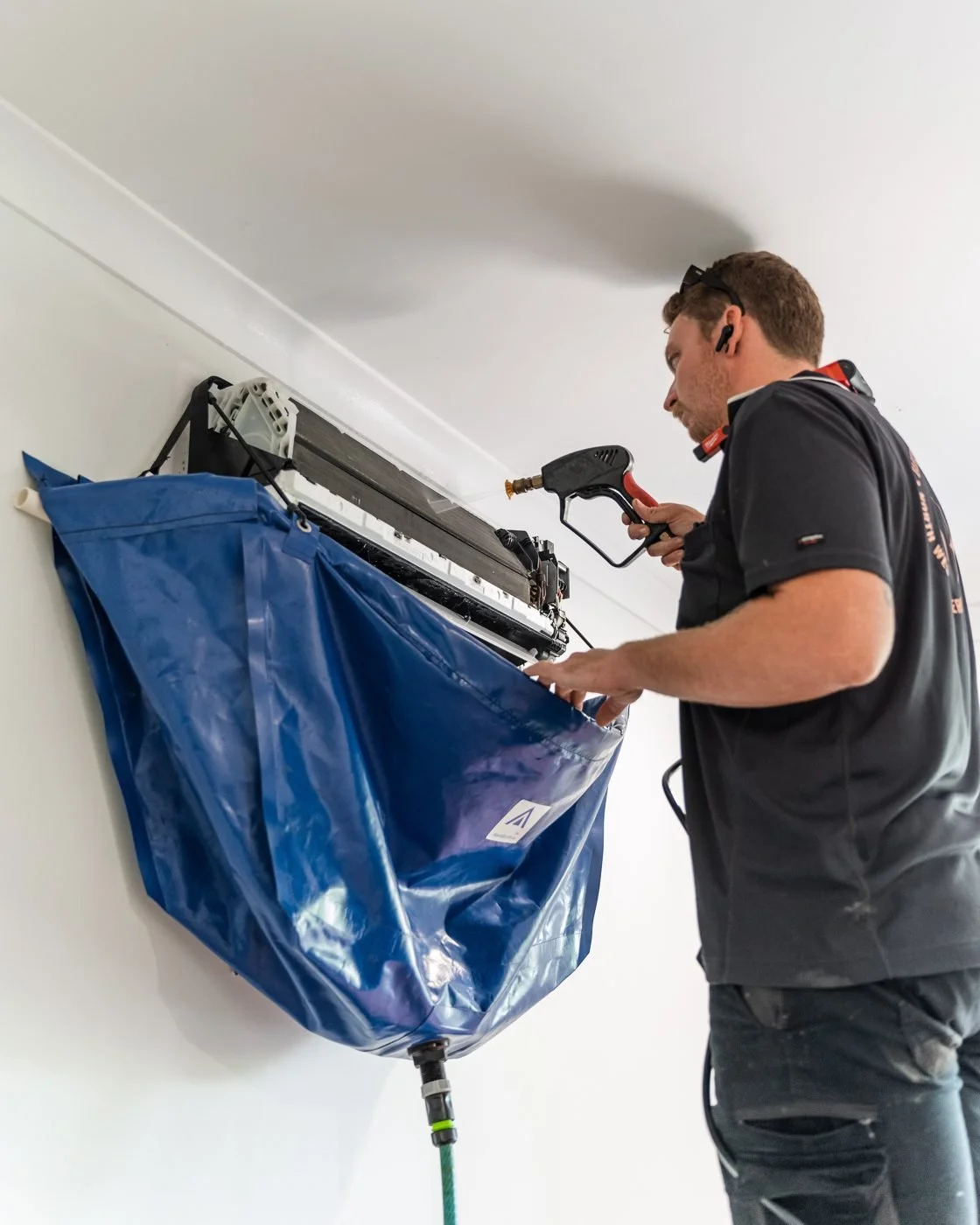 Bazlec West technician coil-cleaning a split system