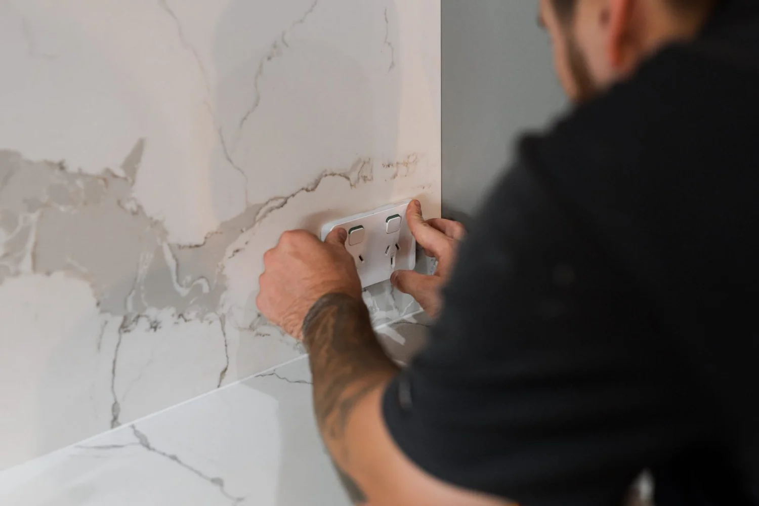 Electrician fitting a powerpoint on a stone splashback