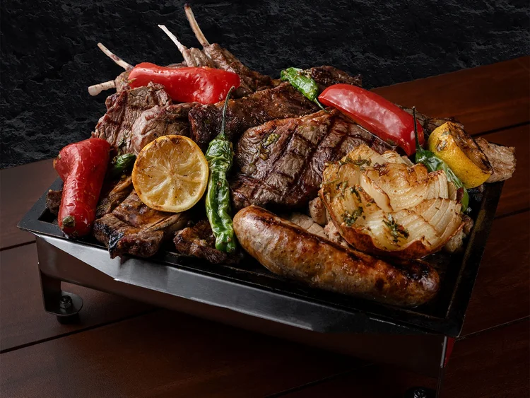 Parrillada grill tray loaded with mixed grilled meats, chorizo, peppers and onion