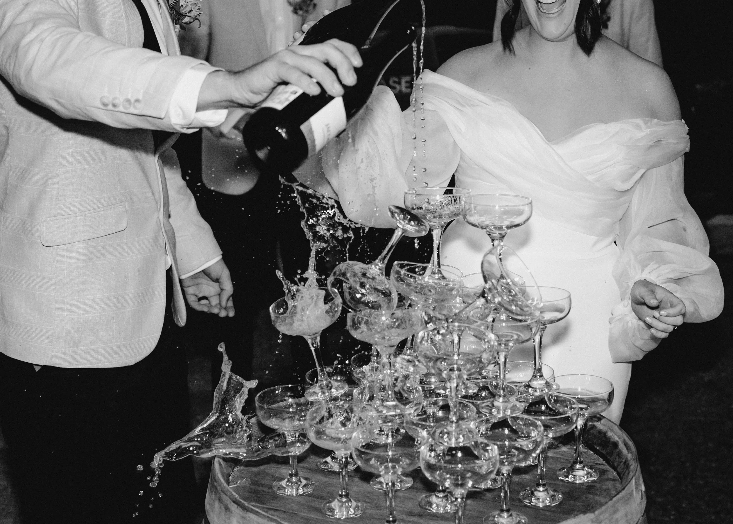 Wedding champagne tower being poured during reception celebration