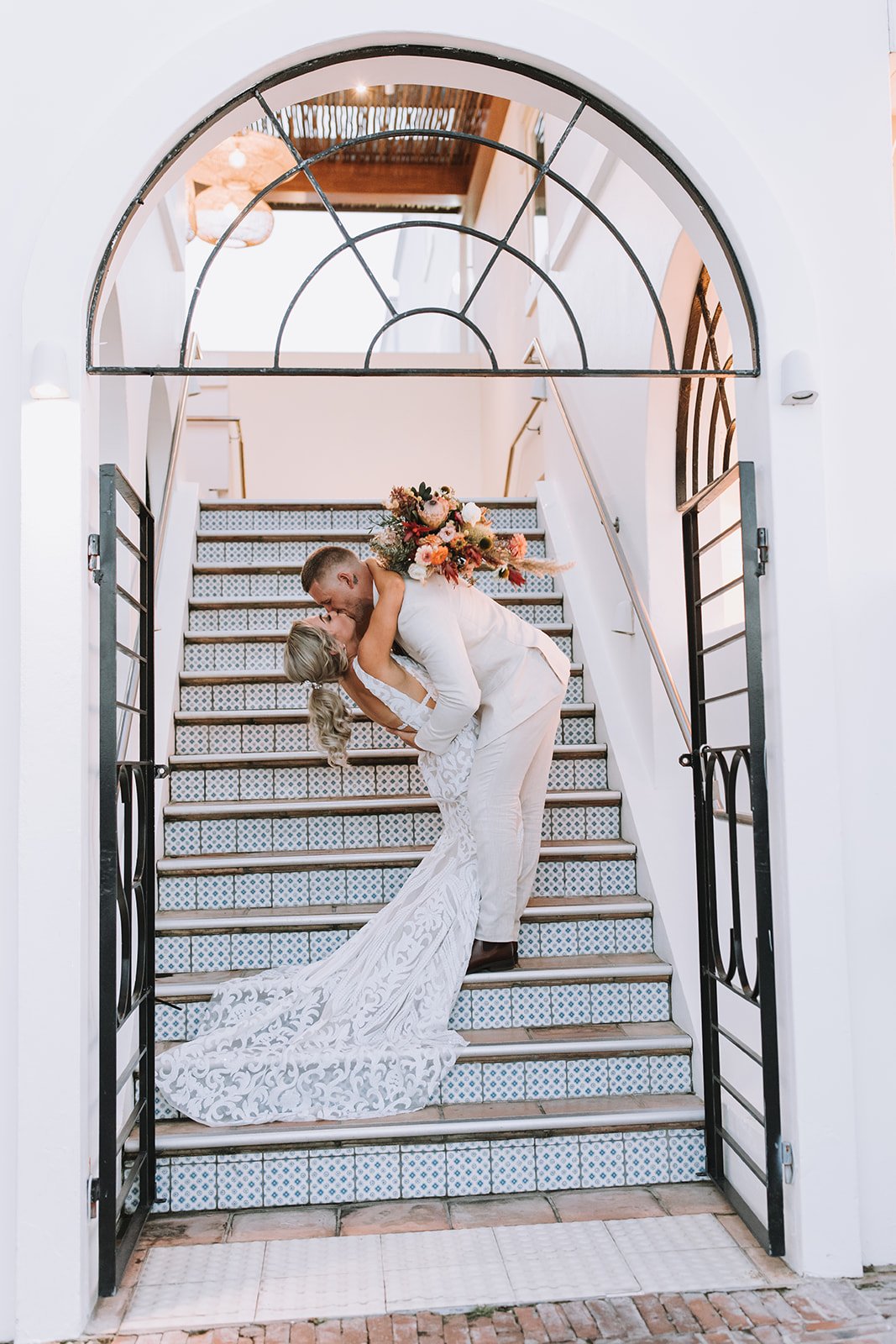 Bride and groom sharing a romantic kiss on the grand staircase of Shoal Bay Country Club. Wedding photography by Nicole Butler Photography.
