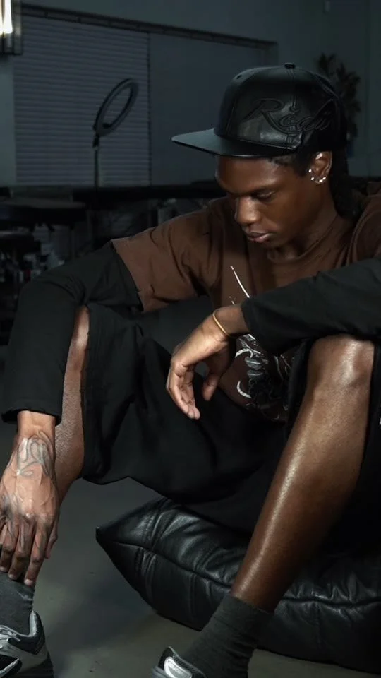 Man in a dark studio with a flowing script hand tattoo
