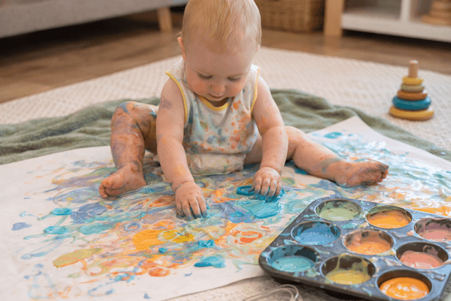 Baby exploring colourful yoghurt paint sensory play, an early childhood activity designed by Joyora