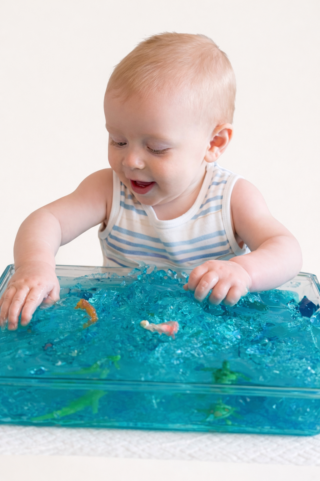 Child digging small toys out of wobbly gelatin, taste-safe sensory activity
