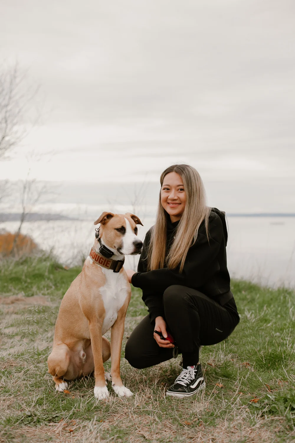 Fyfy kneeling next to her dog Dougie on a grassy bluff