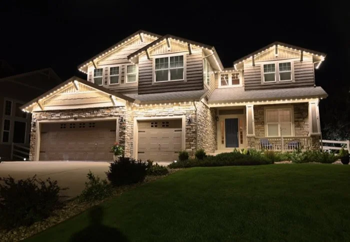 Large two-story home with warm white roofline lighting across multiple gables
