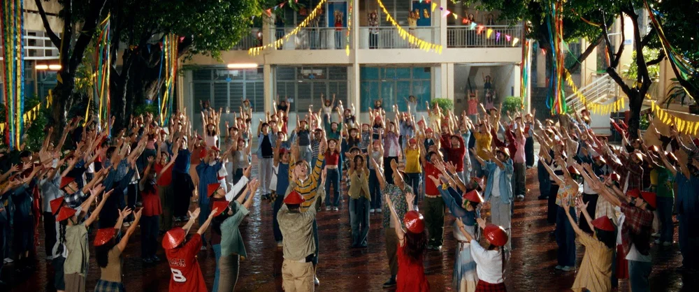 A crowd dances in a courtyard strung with flags