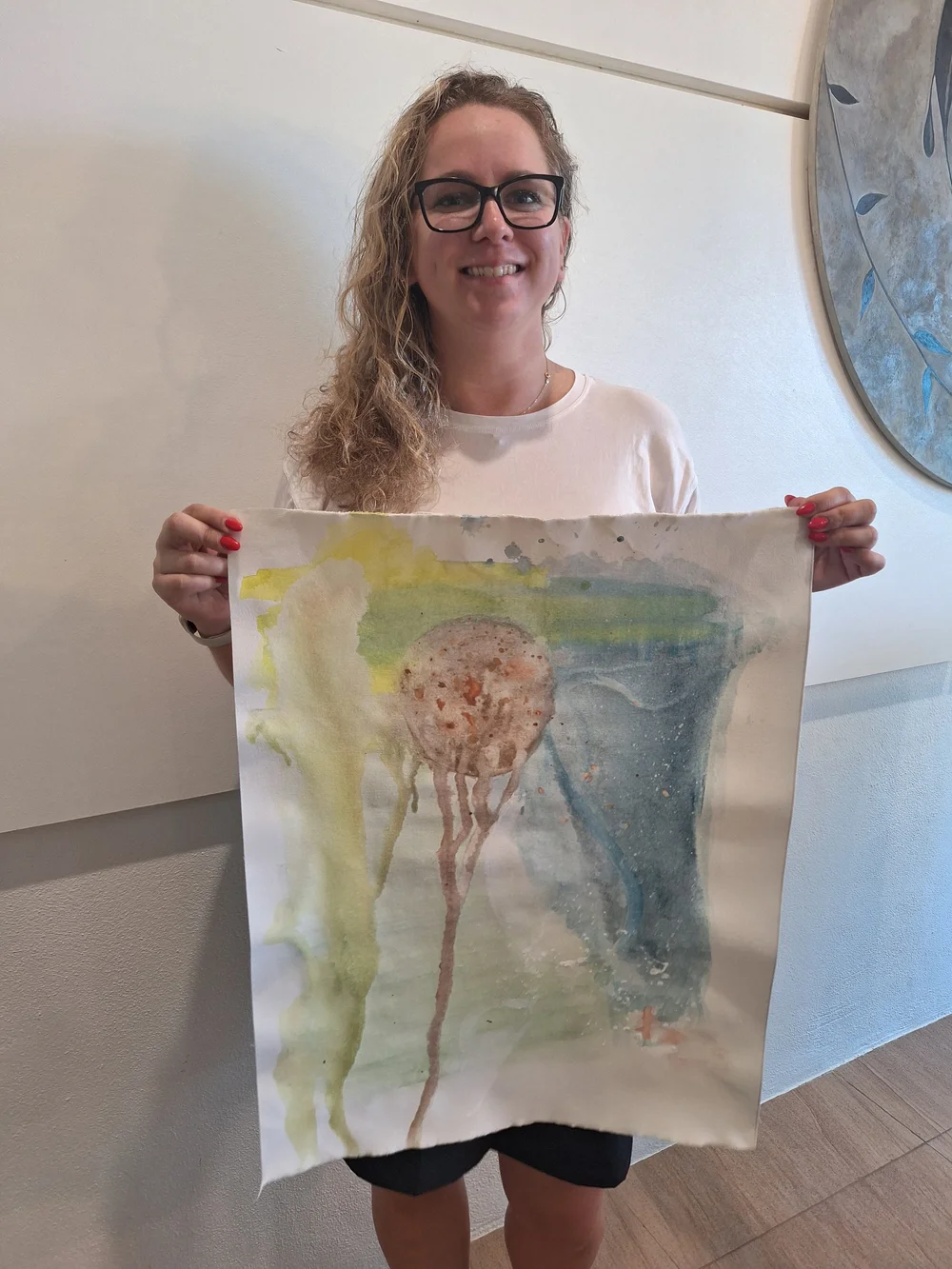 A smiling guest holding up her watercolour painting