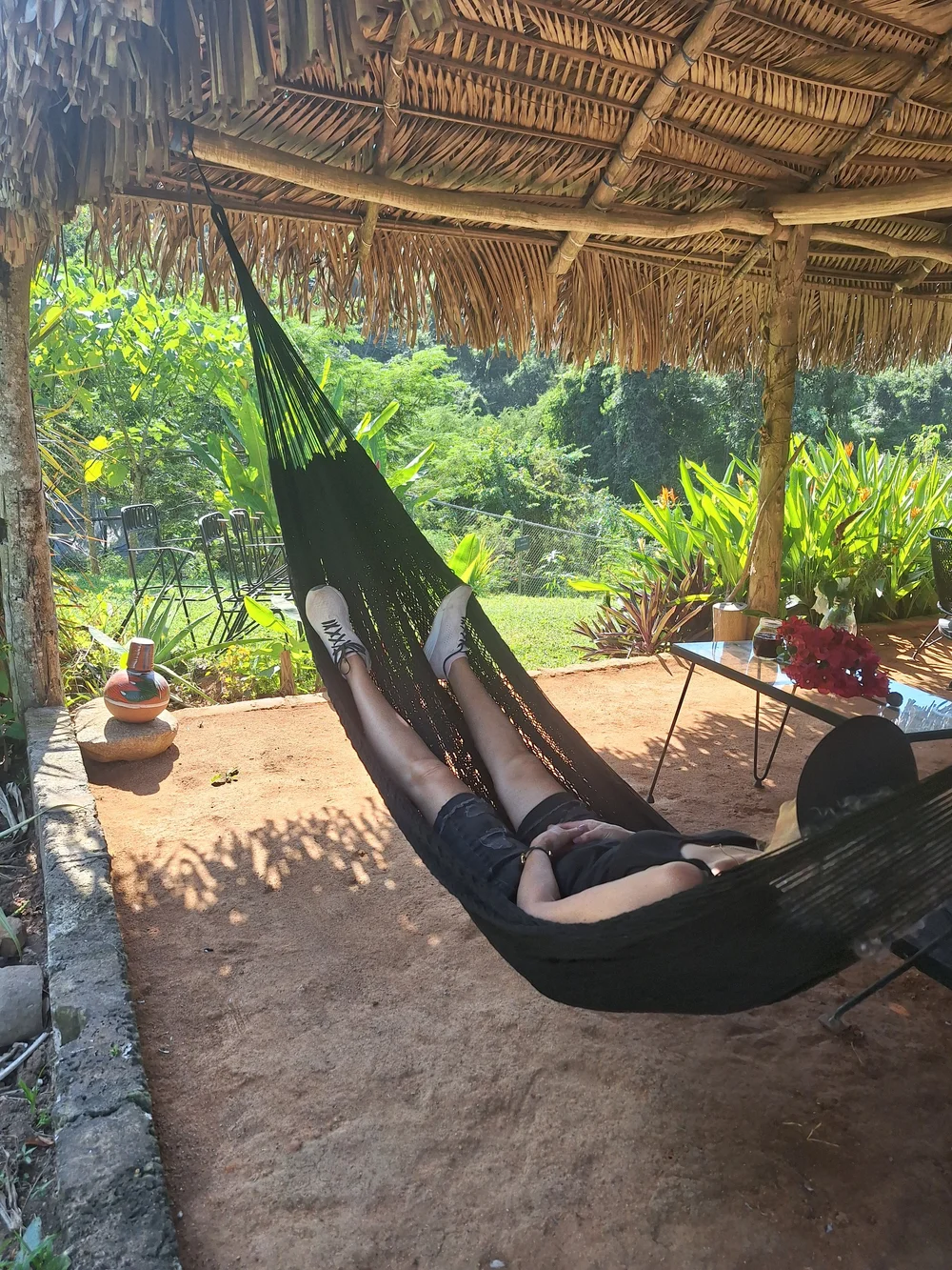 A guest resting in a hammock under a palapa