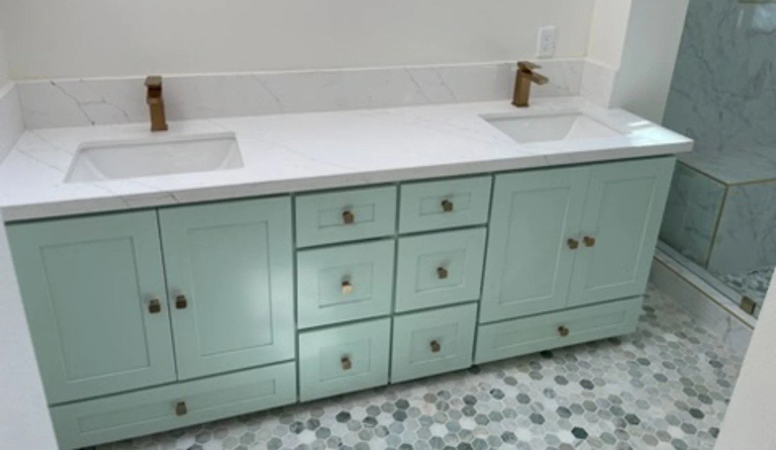Completed pale-green double vanity with two sinks and warm-toned faucets