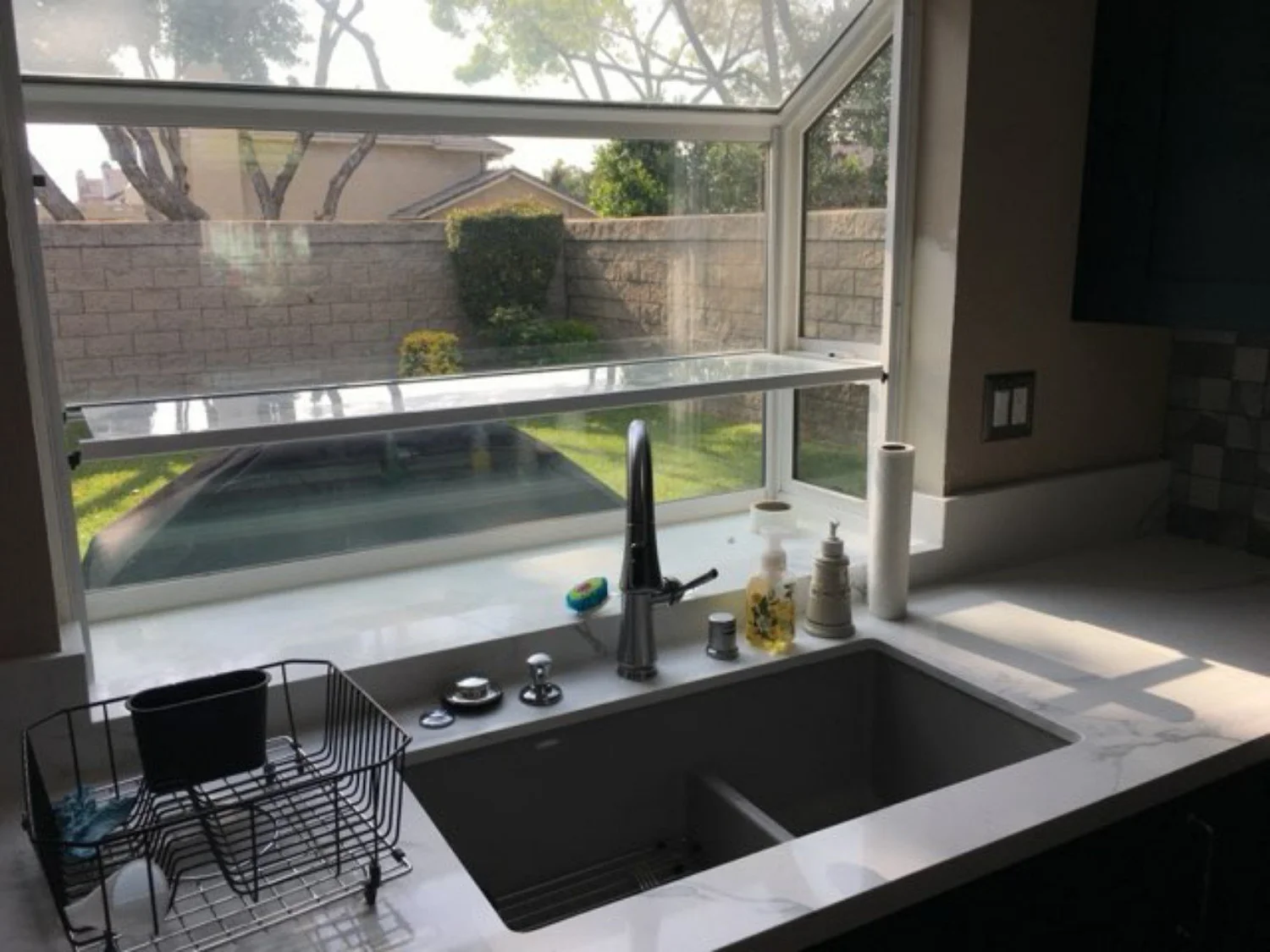 Kitchen sink and counter detail beneath a wide residential window