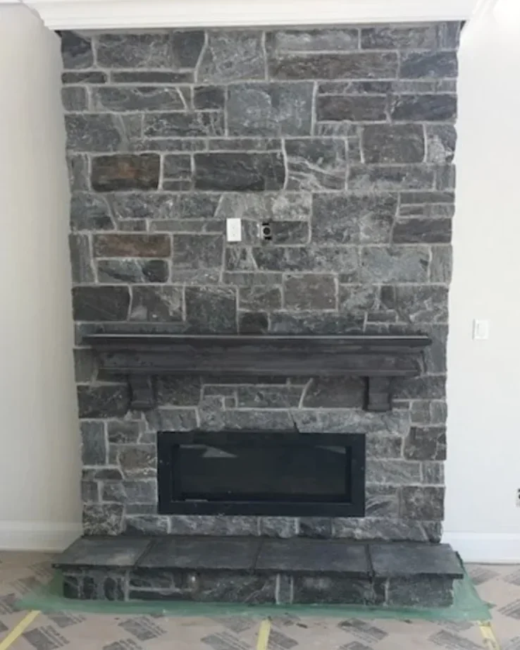 Interior thin stone fireplace with hearth and surround detail.
