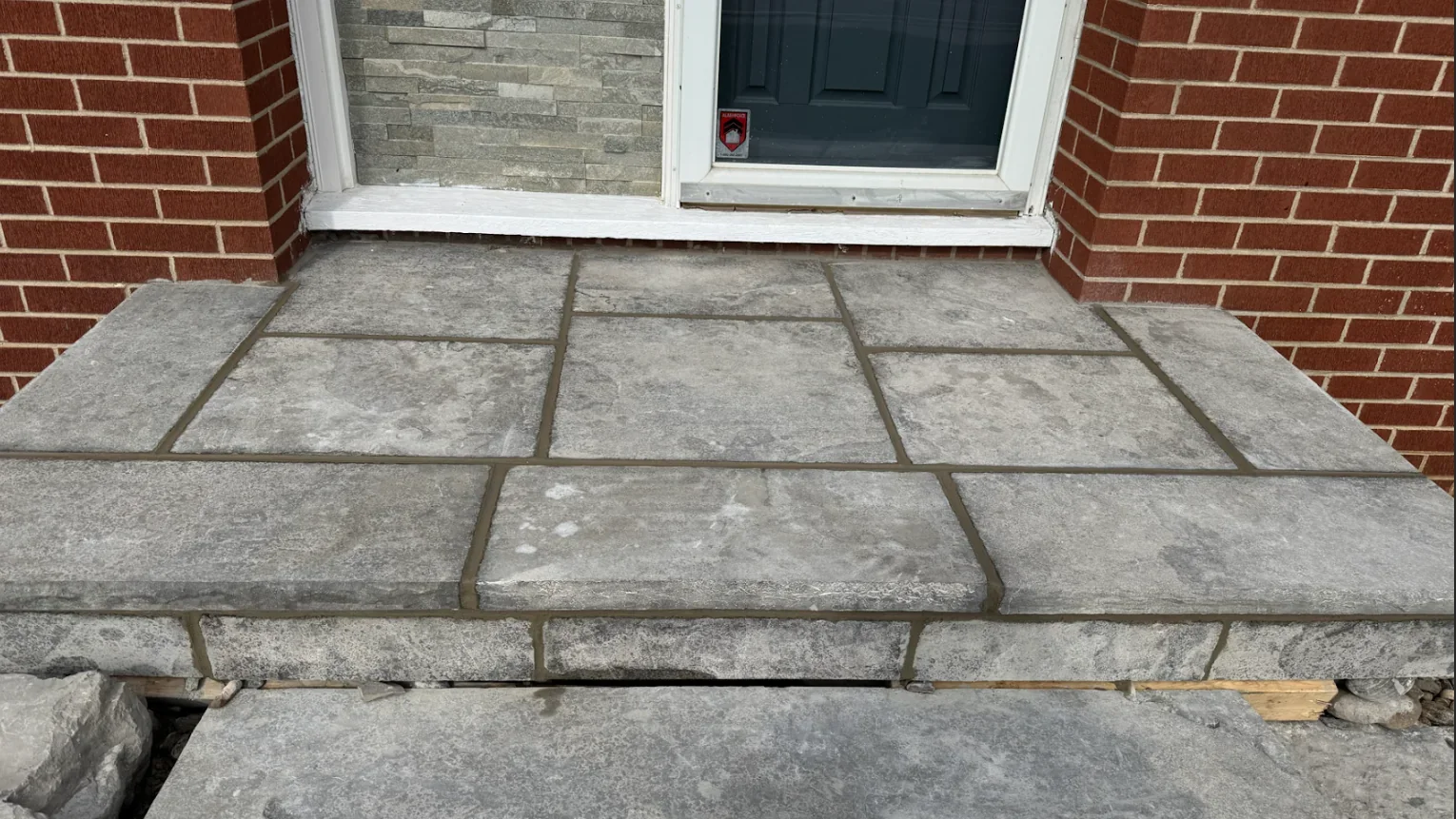 Flagstone entry landing with repointed joints and brick wall context.